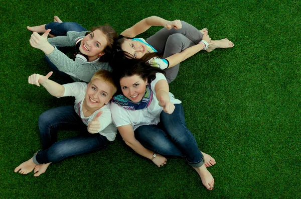 Čtyři mladé ženy sedí na zelené trávě — Stock fotografie
