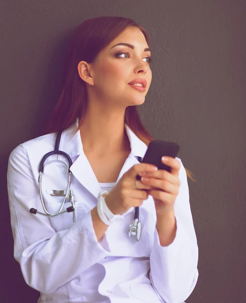 Mujer joven médico sentado en el suelo con su teléfono — Foto de Stock