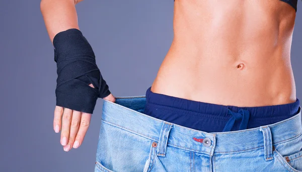 Young fitness woman showing that her old jeans — Stock Photo, Image