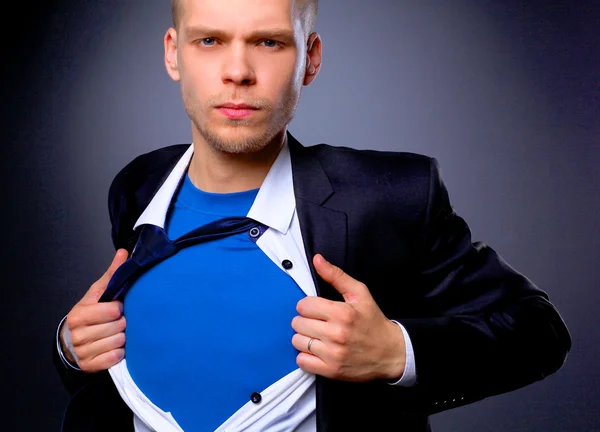 Jonge zakenman handelt zoals een super held en scheuren zijn overhemd, geïsoleerd op grijze achtergrond — Stockfoto