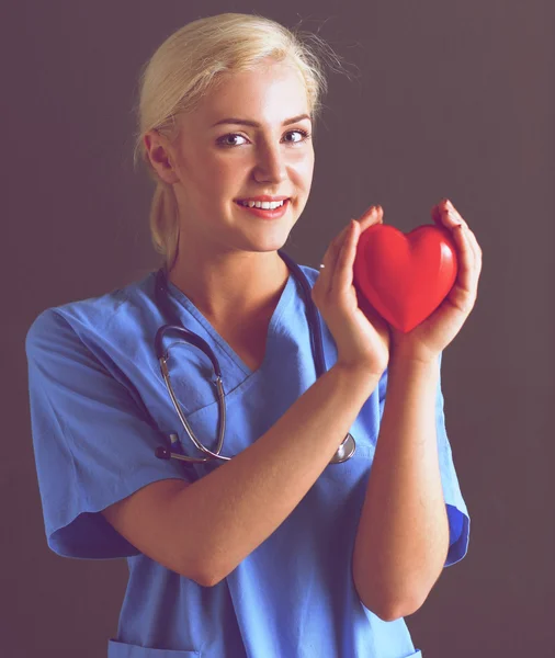 Doctor with stethoscope holding heart, isolated on grey background — Stock Photo, Image