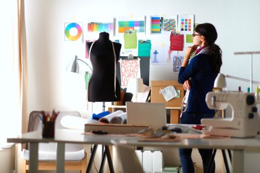 Güzel moda tasarımcısı stüdyoda duruyor.