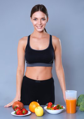 Sebzelerle masanın yanında duran genç ve güzel bir kadın.