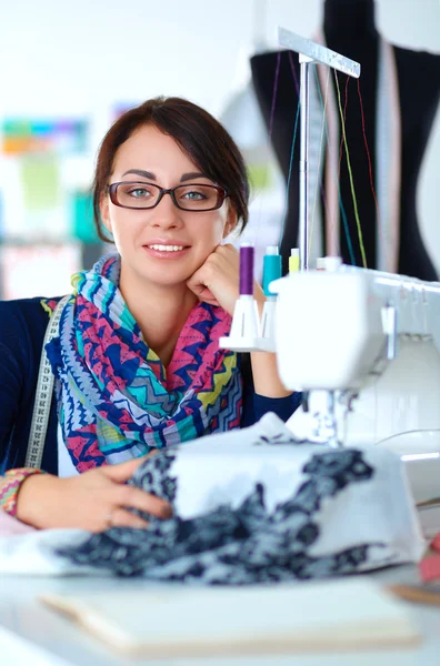 Young woman sewing while sitting at her working place — Stock Photo, Image