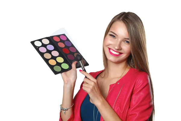 Jonge mooie vrouw houdt in een hand en een palet met verf en schaduwen voor make-up, tweedehands borstel voor make-up — Stockfoto