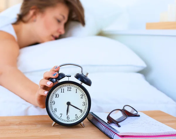 Una mujer joven apagando su despertador por la mañana — Foto de Stock