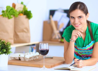 evde bir defter üzerinde yazma onu mutfakta ayakta mutlu güzel kadın