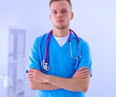 Steteskoplu doktor ayakta, çapraz kollu, beyaz arka planda izole.