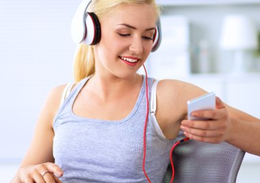 Evdeki genç ve güzel kadın kanepede oturup müzik dinliyor.