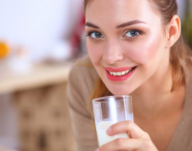 Gülümseyen çekici kadın mutfağın içinde kahvaltı yapıyor.