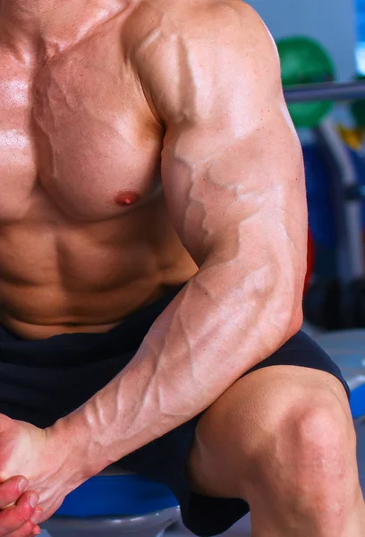 Joven hombre guapo se sienta después del entrenamiento en el gimnasio — Foto de Stock