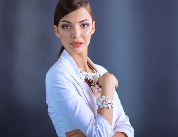 Portrait of young woman with beads, standing on gray background — Stock Photo, Image
