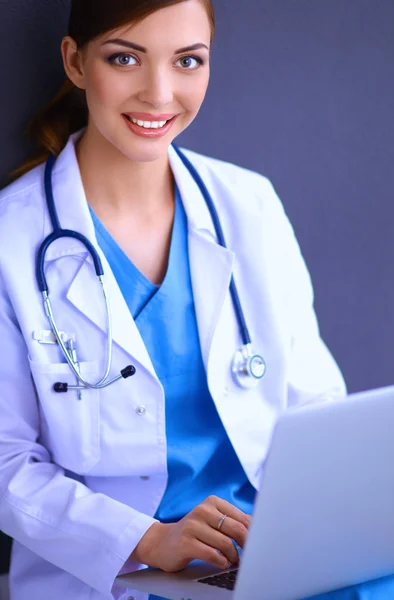 Médico feminino trabalhando sentado em fundo cinza — Fotografia de Stock