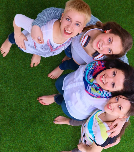 Четыре молодые женщины стоят на зеленой траве — стоковое фото