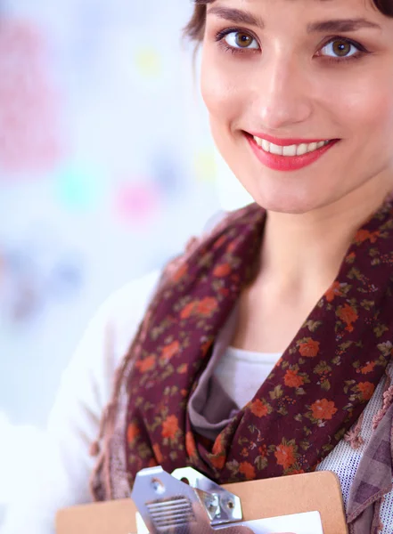 Junge attraktive Modedesignerin steht im Büro am Schreibtisch und hält Ordner in der Hand — Stockfoto