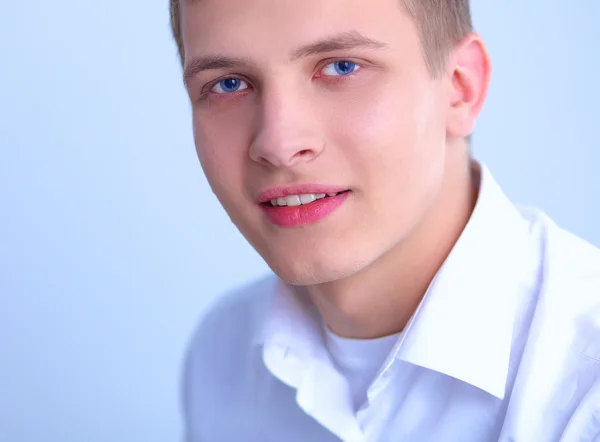 Портрет молодого чоловіка, який посміхається сидячи на сірому фоні — стокове фото