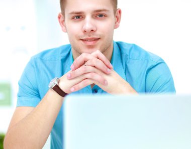 Genç işadamı ofiste çalışıyor, masada oturuyor.