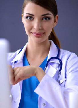 Gri arka planda oturan kadın doktor