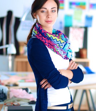 Güzel moda tasarımcısı stüdyoda duruyor.