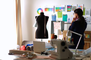 Güzel moda tasarımcısı stüdyoda duruyor.