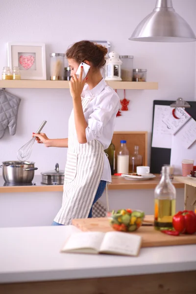 Portret van een lachende vrouw met telefoon in de keuken thuis — Stockfoto