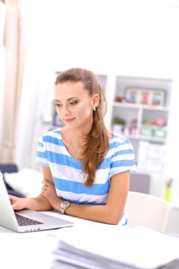 Elinde evrakları olan kadın masanın üstünde oturuyor.