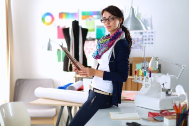 Güzel moda tasarımcısı stüdyoda duruyor.