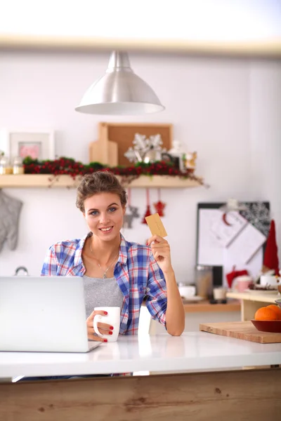 Donna sorridente shopping online con computer e carta di credito in cucina — Foto Stock