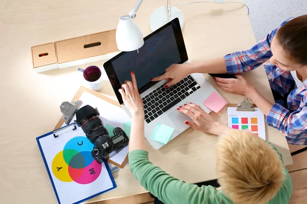 Vrouwelijke fotograaf zittend op het bureau met laptop — Stockfoto