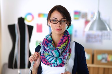 Güzel moda tasarımcısı stüdyoda duruyor.