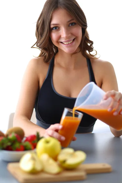 Flicka sitter i köket på skrivbord med frukt och glas med juice — Stockfoto