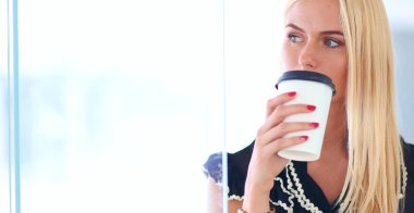 Ofiste kahve içen genç bir kadın.