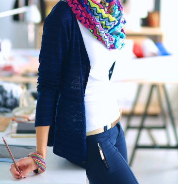 Güzel moda tasarımcısı stüdyoda duruyor.