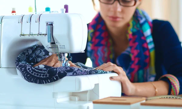 Junge Frau näht, während sie am Arbeitsplatz sitzt — Stockfoto