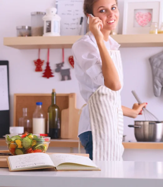 Portret van een lachende vrouw met telefoon in de keuken thuis — Stockfoto