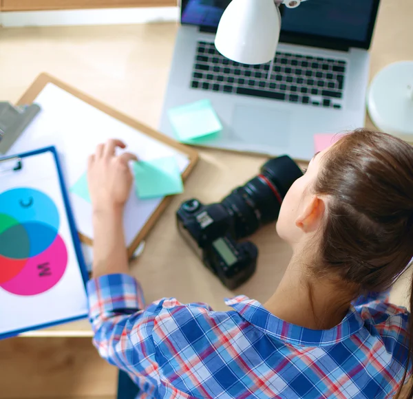 Vrouwelijke fotograaf zittend op het bureau met laptop — Stockfoto