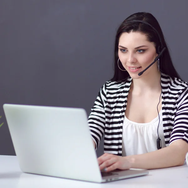 Mooie zakenvrouw werken aan haar bureau met headset en laptop — Stockfoto