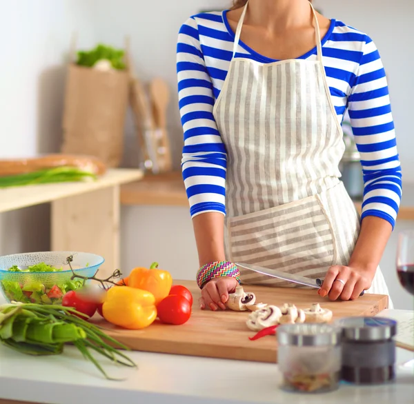 Jeune femme coupant des légumes dans la cuisine — Photo