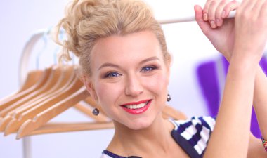 Raf ofiste askıları ile yakınındaki güzel genç stilist