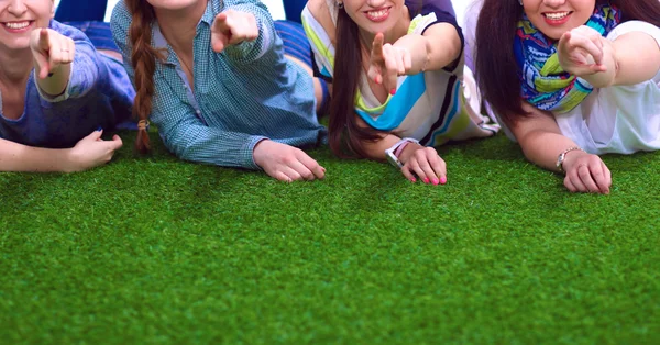 Vier junge Frauen liegen auf grünem Gras — Stockfoto