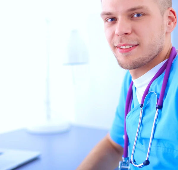 Ritratto di un medico maschio sorridente con computer portatile seduto alla scrivania nello studio medico — Foto Stock