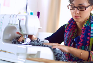 Çalışırken dikiş diken genç bir kadın.