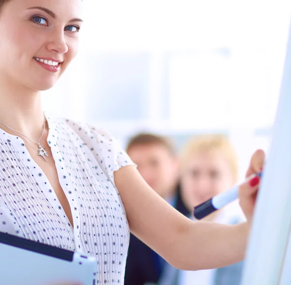 Businesswoman writing on flipchart while giving presentation to colleagues in office — Stock Photo, Image