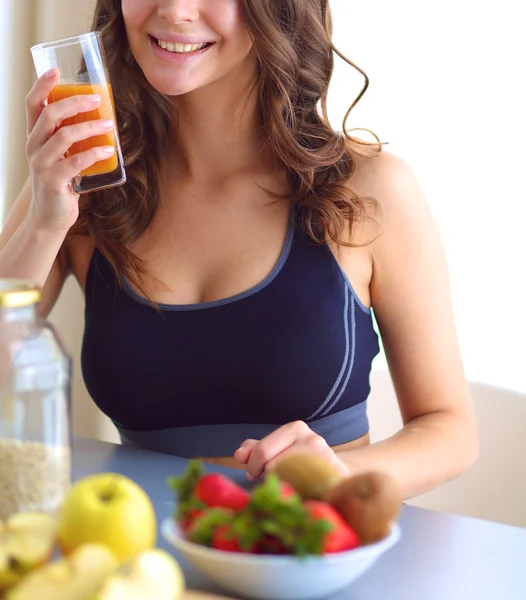 Flicka sitter i köket på skrivbord med frukt och glas med juice — Stockfoto