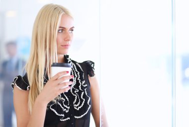 Ofiste bir fincan kahve ayakta tutan işkadını