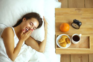 Genç ve güzel bir kadın yatakta yatıyor.