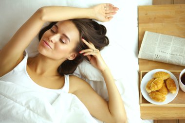 Genç ve güzel bir kadın yatakta yatıyor.