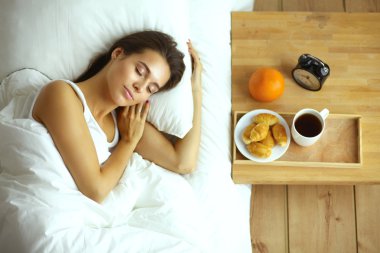 Genç ve güzel bir kadın yatakta yatıyor.