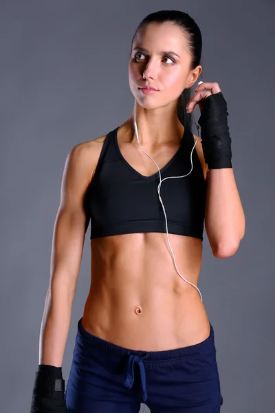 Muscular young woman posing in sportswear against black background — Stock Photo, Image