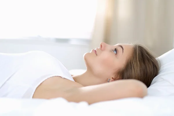 En vacker ung kvinna ligger i sängen bekvämt och lyckligt — Stockfoto